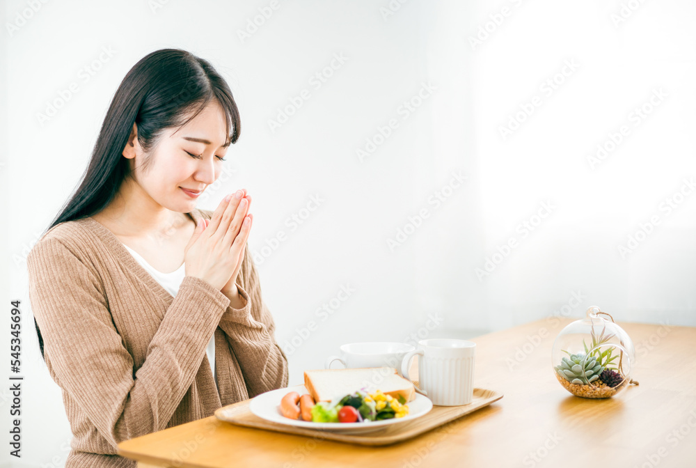 家でご飯を食べる日本人女性（いただきます）

