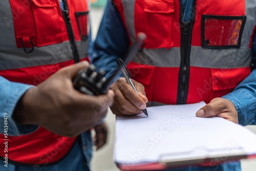 Close up portrait photo of the moment of two black african male container engineers doing report checking on their clip board at a shipping yard of a local logistic freight forwarder company