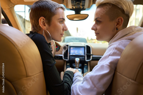 Female LGBT couple sits in a beautiful car