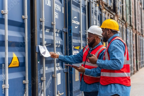 Fotografia Two black african male professional engineers inspecting a container in a logist