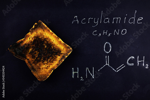 inscription chemical formula of acrylamide and black burnt bread toast containing acrylamide on a black background