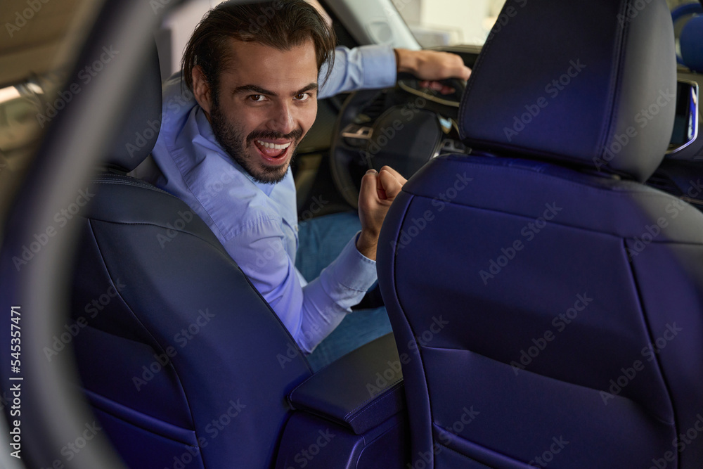 Joyous man posing for camera in his motorcar