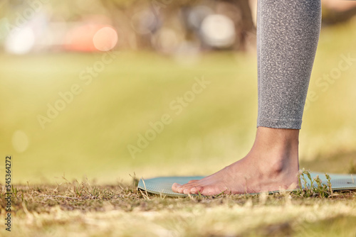 Woman feet, mat and yoga on grass, park and exercise, meditation and spiritual wellness in nature for zen. Female, pilates or cardio person with workout training for peace, calm and healthy lifestyle