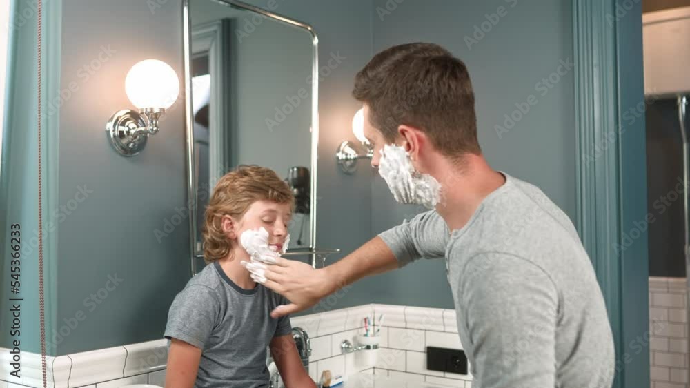 Close up of cute kid in bathroom with adult dad has face covered in