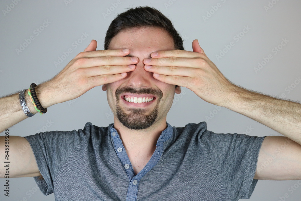 Happy young man covering eyes with both hands
