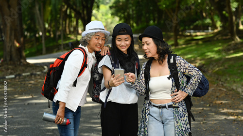 Middle age women and teenage woman walking nature park and using navigator on smart phone. Technology and travel adventure concept
