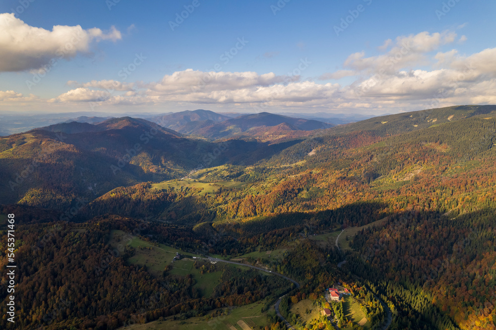 Beautiful trees on the tops of the Carpathian mountains on a warm autumn day on the Synevyr Pass ridge and white clouds on blue sky background. Ukraine