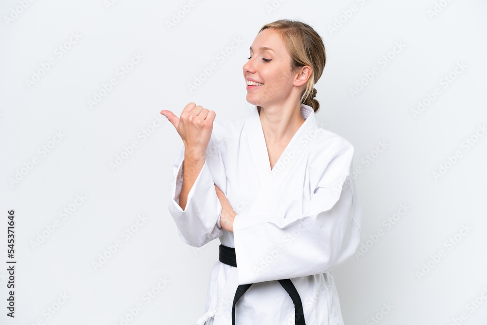 Young caucasian woman doing karate isolated on white background pointing to the side to present a product Young caucasian woman doing karate isolated on white background pointing to the side to present a product