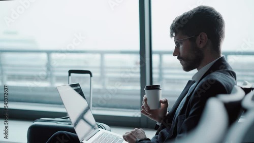 business man with a laptop waiting for his flight in the airport lounge.