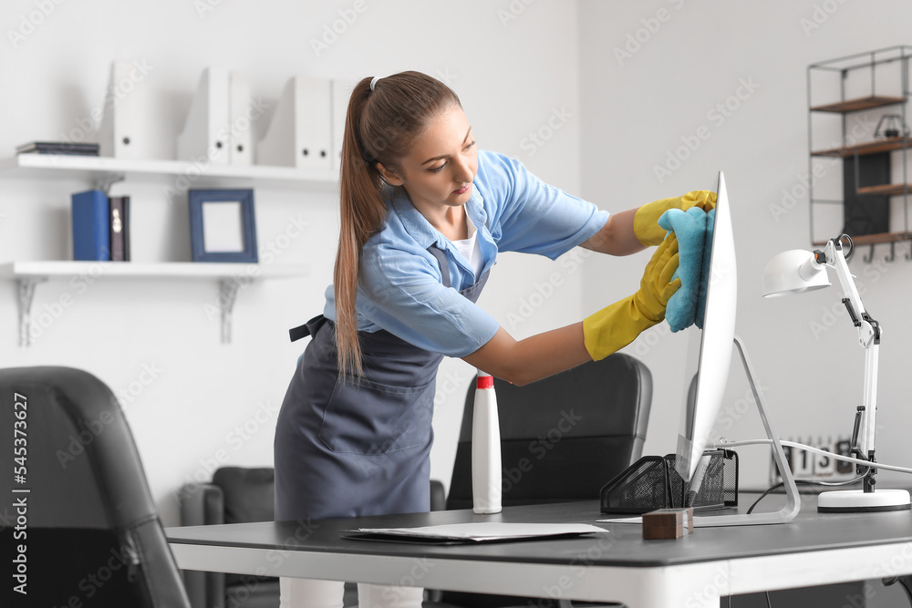 Female worker of cleaning service wiping computer screen in office Female worker of cleaning service wiping computer screen in office