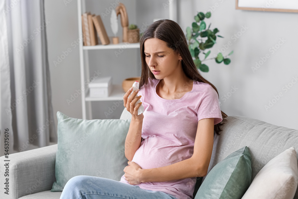 Young pregnant woman with nosebleed and tissue at home Young pregnant woman with nosebleed and tissue at home