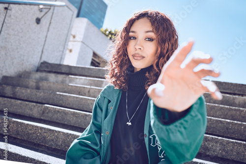 Fashion, trendy and portrait of a woman in the city with a stylish, edgy and street wear outfit. Youth, stylish and girl model from Mexico posing with her hand in an outdoor road in a urban town. photo