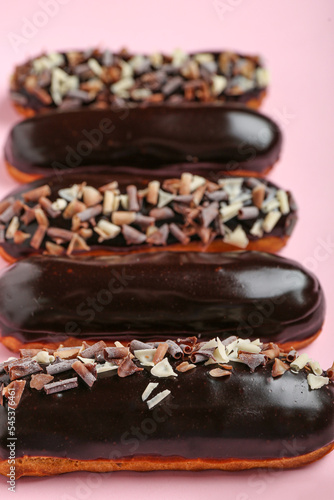 Delicious chocolate eclairs on pink background, closeup