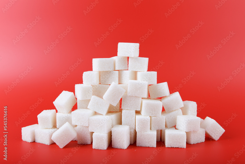 heap of white sugar cubes isolated on red background heap of white sugar cubes isolated on red background
