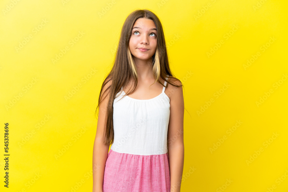 Little caucasian girl isolated on yellow background and looking up Little caucasian girl isolated on yellow background and looking up