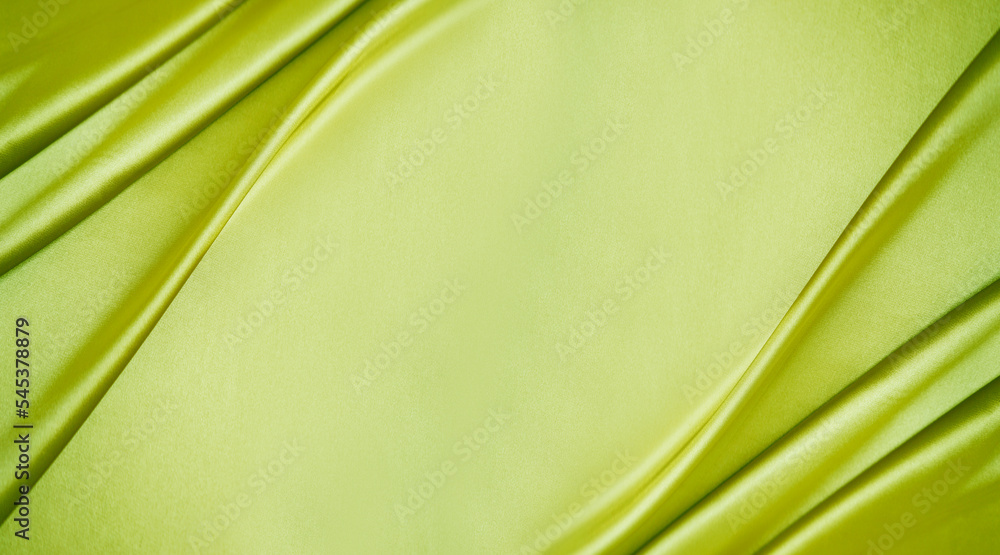 Yellow green silk satin. Lime color shiny silky smooth fabric. Soft wavy folds. Elegant background with space for design. Bright. Light. Banner. Flat lay, top view table. Template.