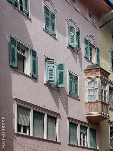 Old historic architecture in Italy. Traditional European old town building. Wooden windows, shutters and colourful pastel walls with sunlight shadows. Aesthetic summer vacation travel background © Floral Deco