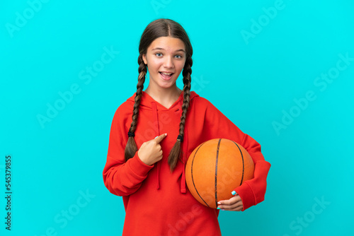 Little caucasian girl playing basketball isolated on blue background with surprise facial expression © luismolinero