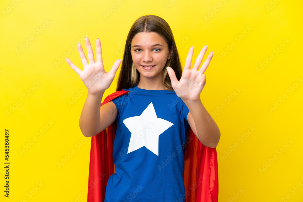 Little caucasian superhero girl isolated on yellow background counting nine with fingers Little caucasian superhero girl isolated on yellow background counting nine with fingers
