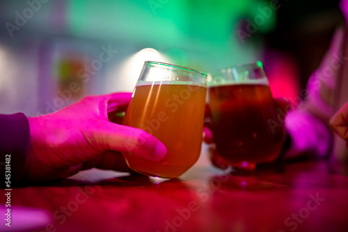 Two friends hands with glasses of craft beer at the pub or bar. taproom