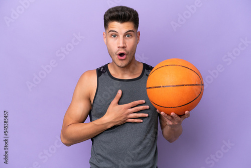 young caucasian woman basketball player man isolated on purple background surprised and shocked while looking right