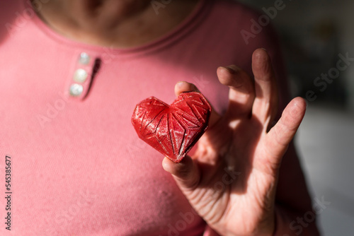 Woman’s hands holding red 3d printed heart. Ideal for diverse concept : love and health, gratitude and charity either technology