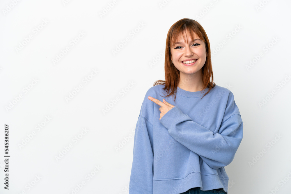 Redhead girl isolated on white background pointing to the side to present a product Redhead girl isolated on white background pointing to the side to present a product