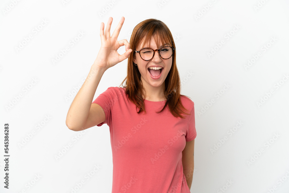 Redhead girl isolated on white background showing ok sign with fingers Redhead girl isolated on white background showing ok sign with fingers