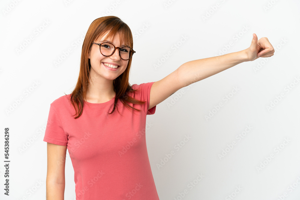 Redhead girl isolated on white background giving a thumbs up gesture Redhead girl isolated on white background giving a thumbs up gesture