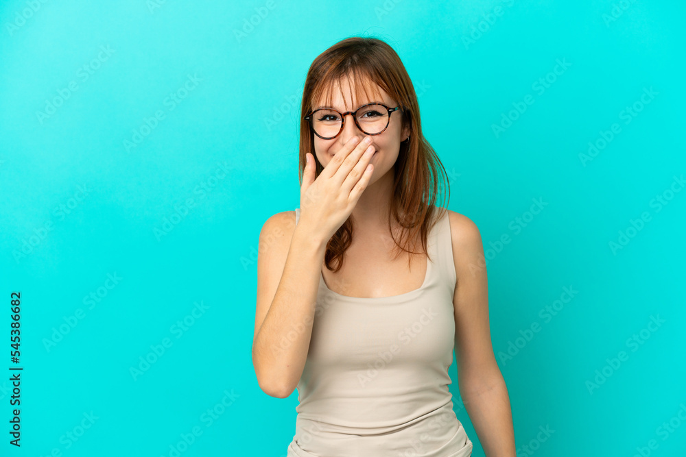 Redhead girl isolated on blue background happy and smiling covering mouth with hand Redhead girl isolated on blue background happy and smiling covering mouth with hand
