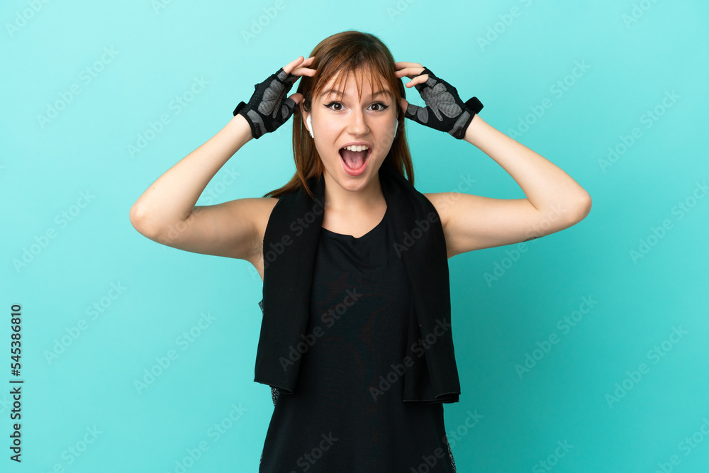Redhead sport girl isolated on blue background with surprise expression Redhead sport girl isolated on blue background with surprise expression