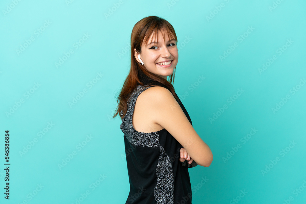 Redhead sport girl isolated on blue background with arms crossed and happy Redhead sport girl isolated on blue background with arms crossed and happy