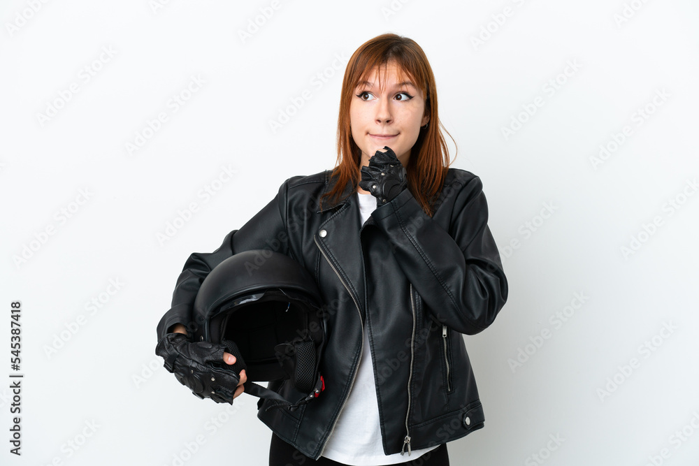 Redhead girl with a motorcycle helmet isolated on white background having doubts and thinking Redhead girl with a motorcycle helmet isolated on white background having doubts and thinking