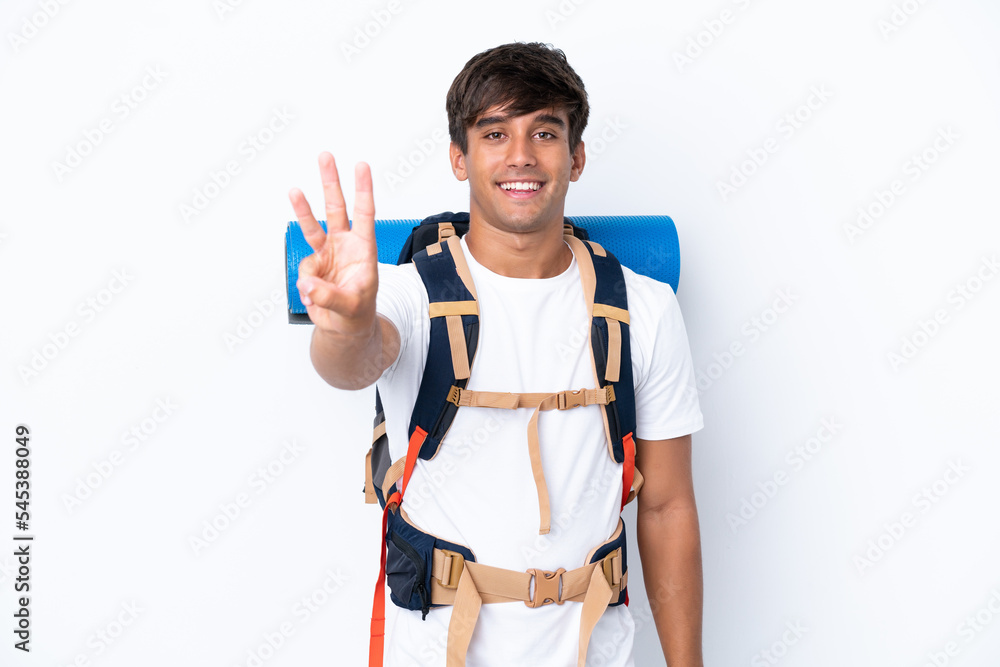 Young mountaineer woman with a big backpack over isolated white background happy and counting three with fingers Young mountaineer woman with a big backpack over isolated white background happy and counting three with fingers