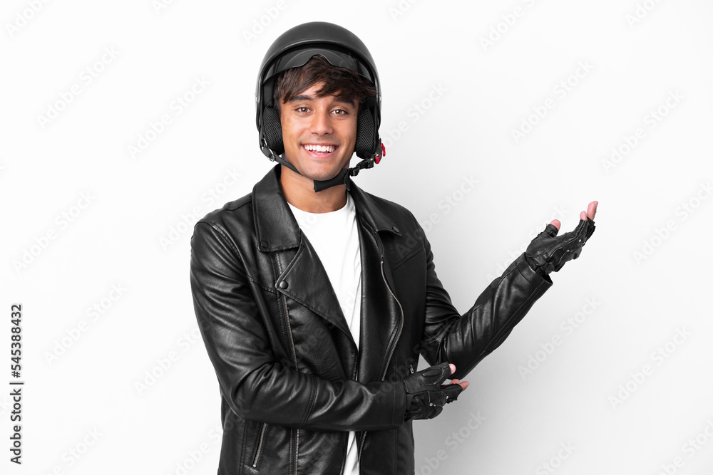 Young man with a motorcycle helmet isolated on white background extending hands to the side for inviting to come Young man with a motorcycle helmet isolated on white background extending hands to the side for inviting to come