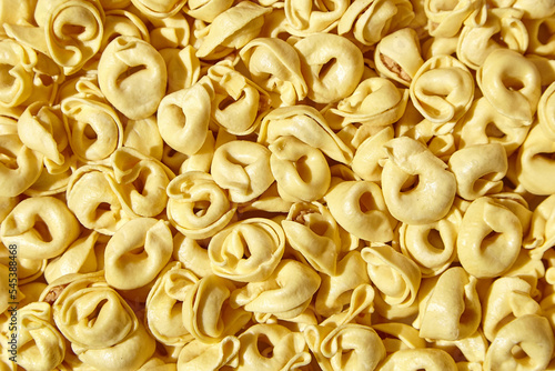 Tortellini pasta with prosciutto, food background, top view. Italian stuffed pasta