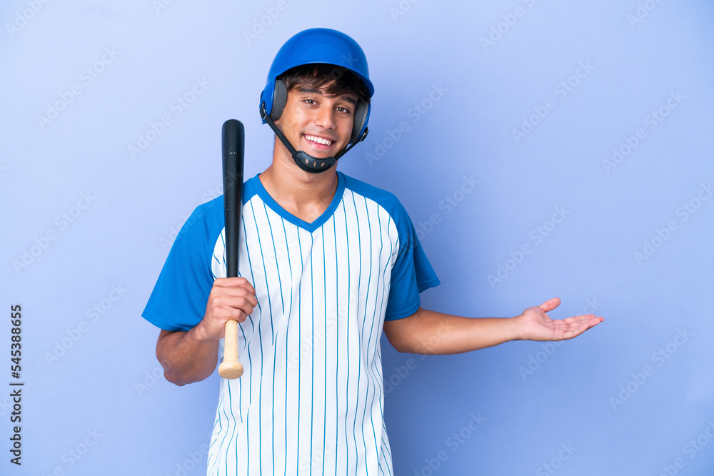 Baseball caucasian man player with helmet and bat isolated on blue background extending hands to the side for inviting to come Baseball caucasian man player with helmet and bat isolated on blue background extending hands to the side for inviting to come