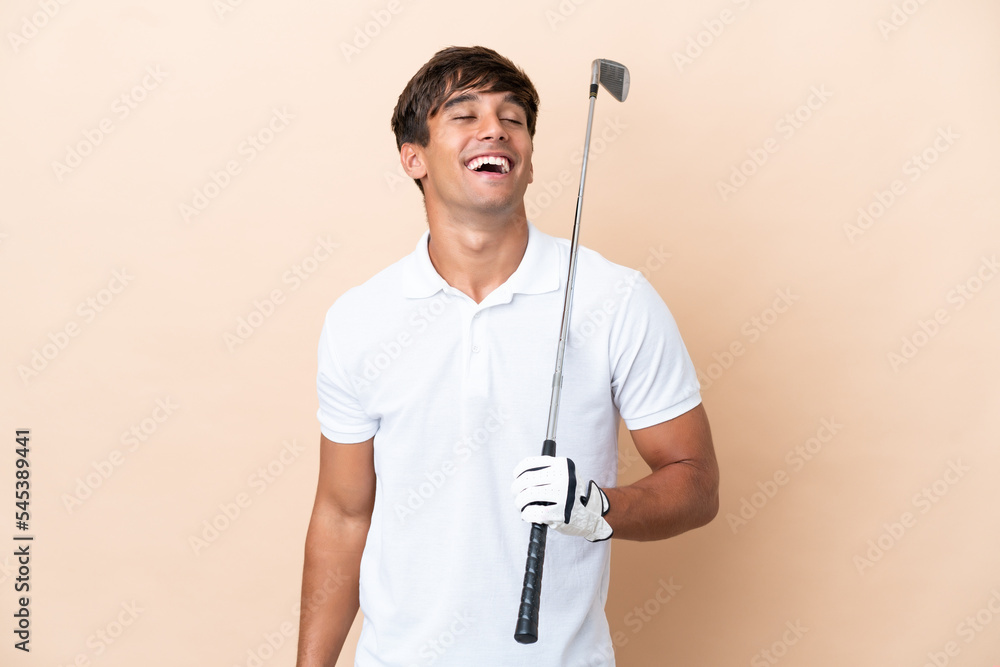 Young golfer player man isolated on ocher background laughing Young golfer player man isolated on ocher background laughing