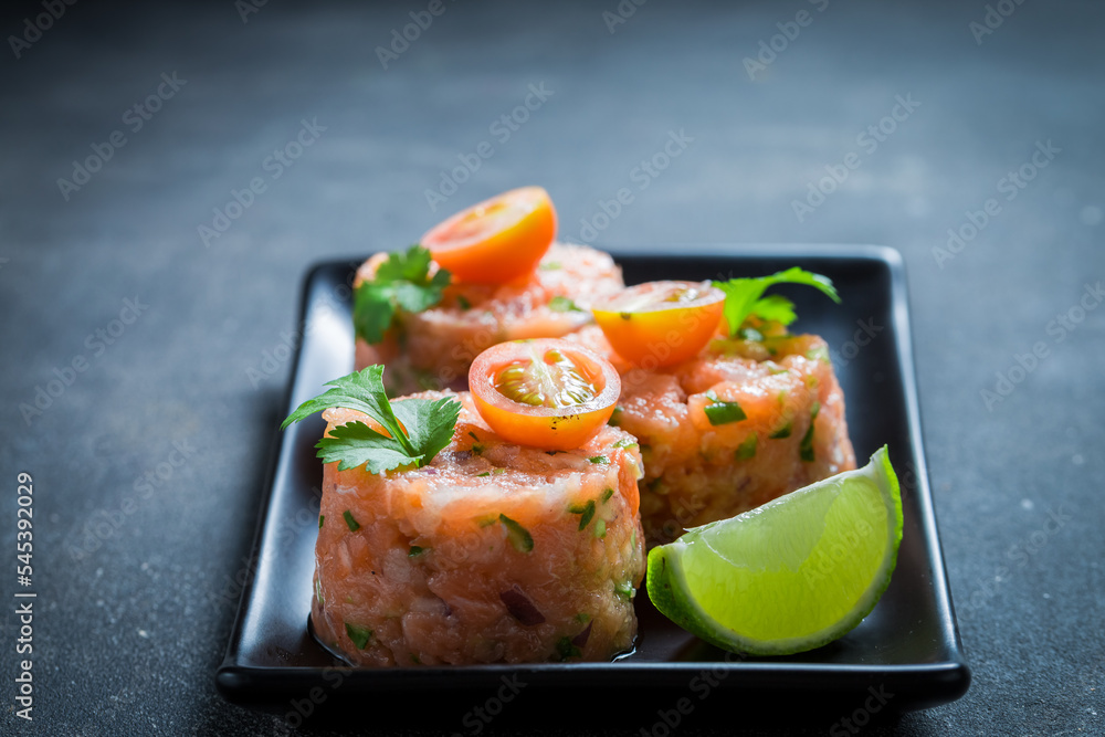 Fresh and raw salmon tartare with cherry tomatoes and lime. Fresh and raw salmon tartare with cherry tomatoes and lime.