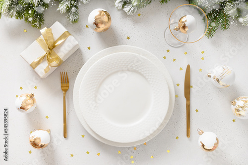 Obraz na plátně Golden Christmas table setting with white plate, gift, golden balls on white background