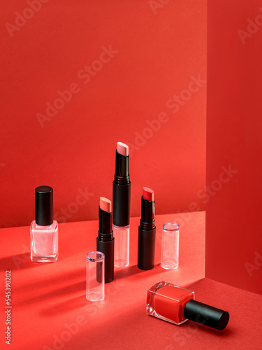 Composition with makeup products. Lipstick and nail polish. Cosmetic products advertisement on red background with Hard light. Product Advertising environment. Sale of beauty products concept. © shyrokova