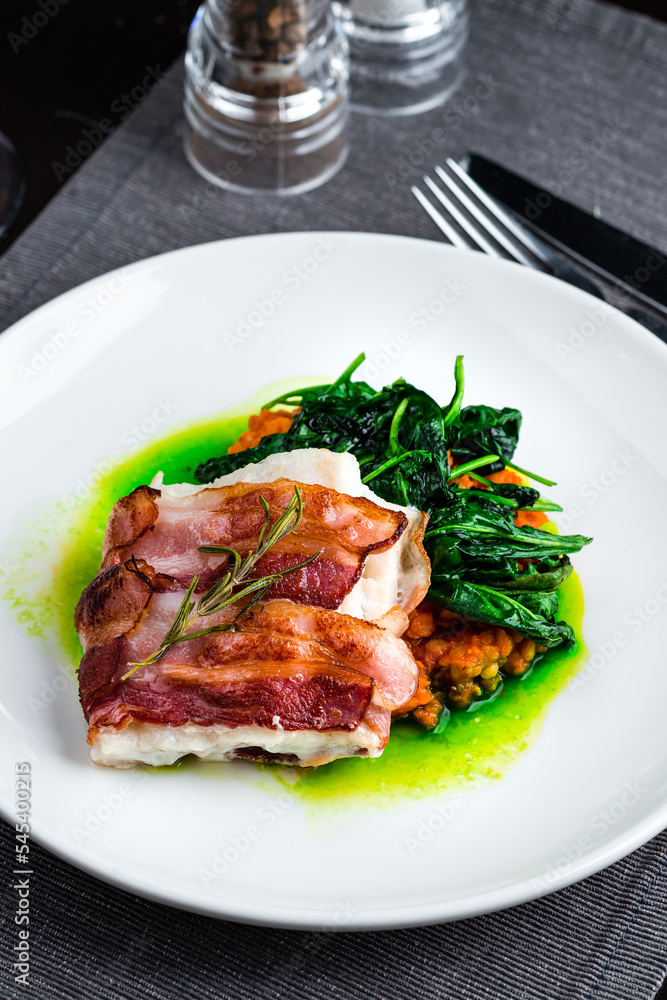 Italian dish, Saltimbocca, of veal fried with prosciutto, Parma ham, sage and green sauce on a plate.