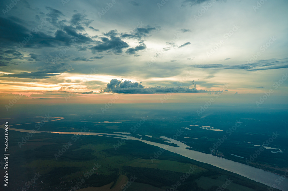 Panoramic aerial view. landscape view from airplane window. Airliner flying in high cloudy sky. airplane is flying in the blue sky with multicolored clouds at sunset. Travel background. Panoramic aerial view. landscape view from airplane window. Airliner flying in high cloudy sky. airplane is flying in the blue sky with multicolored clouds at sunset. Travel background.