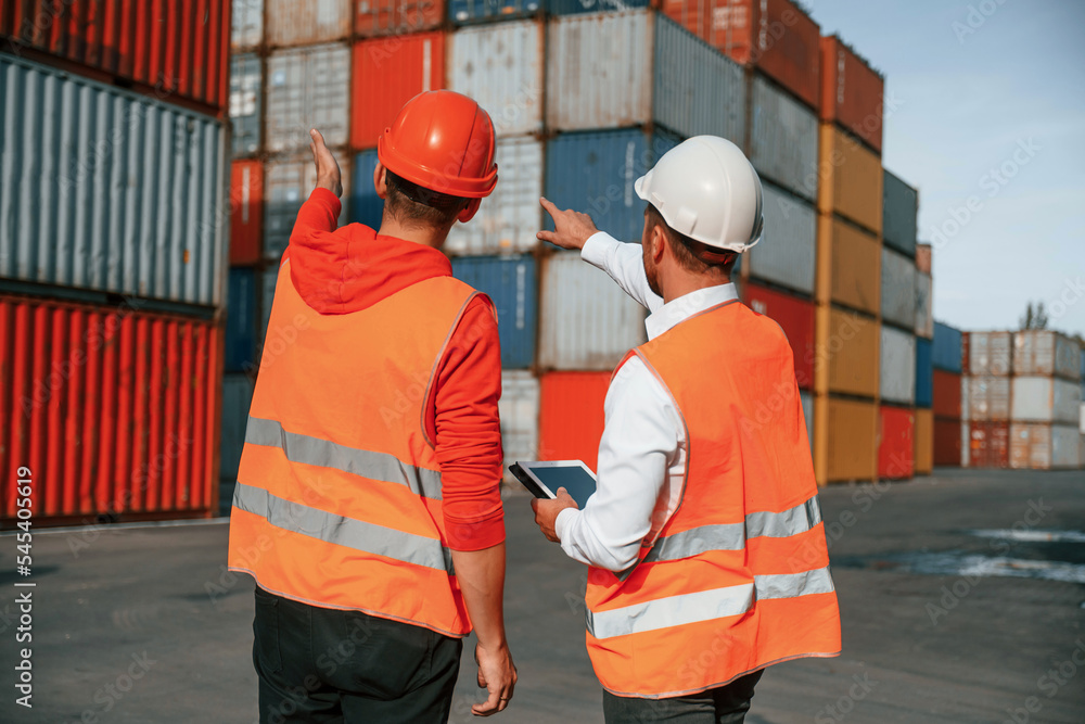 Showing the objects. Two male workers is on the location with containers Showing the objects. Two male workers is on the location with containers