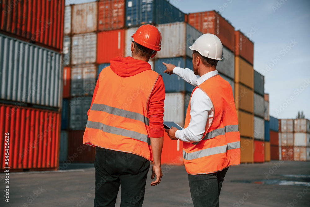 Showing the objects. Two male workers is on the location with containers Showing the objects. Two male workers is on the location with containers