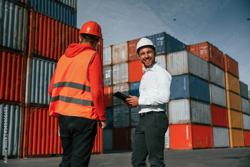 Two male workers is on the location with containers Two male workers is on the location with containers