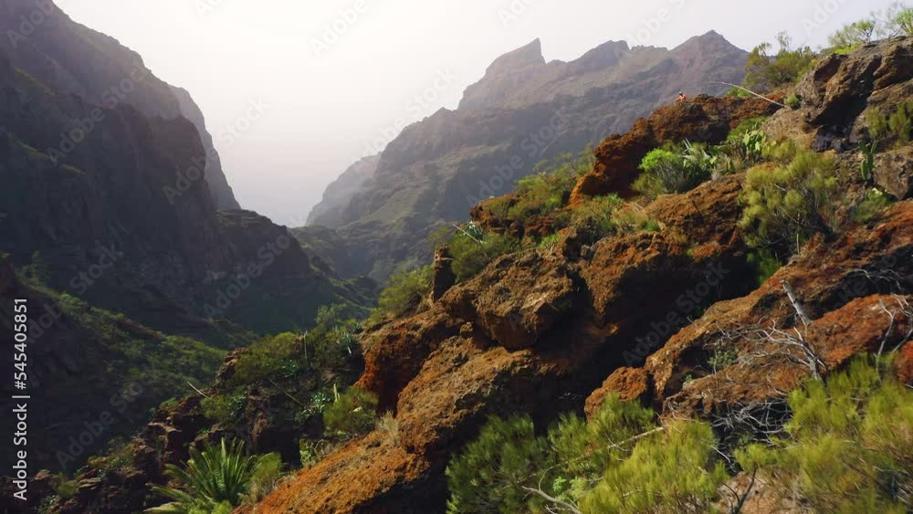 Spectacular aerial view range cliffs, steep crags of Masca Gorge. Famous touristic destination. Tenerife Canary Island Spain. Small cozy settlement village on side of a mountain.