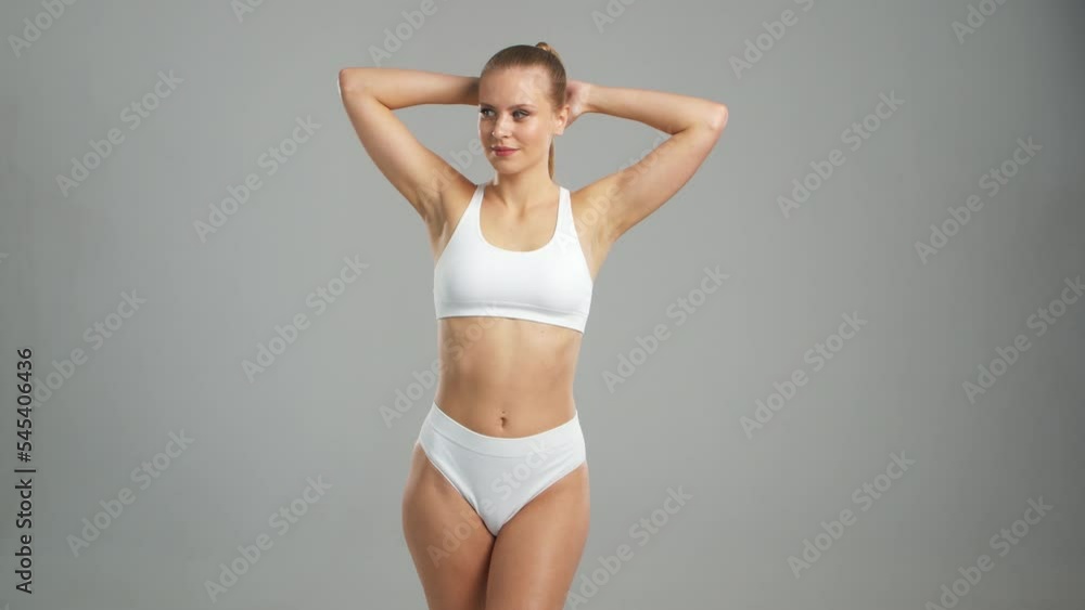 Young, fit and beautiful blond woman in white swimsuit posing over grey background. Healthcare, diet, sport and fitness concept. Young, fit and beautiful blond woman in white swimsuit posing over grey background. Healthcare, diet, sport and fitness concept.