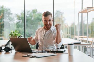 Successful project. Concept of celebration and happiness. Man in formal clothes is working in the modern office