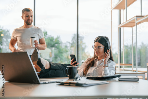 Sitting with legs on the table. Man and woman are working in the modern office together